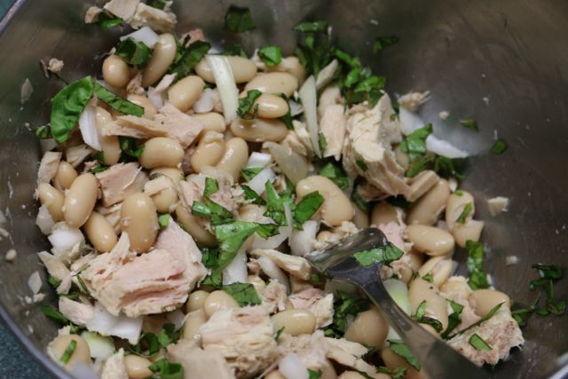 In a large bowl, combine beans, tuna, tomatoes, red onions and basil